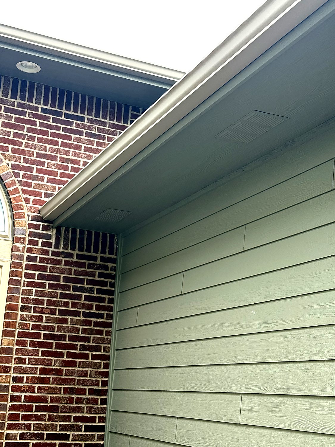 Gutter run along a brick and lap-siding home