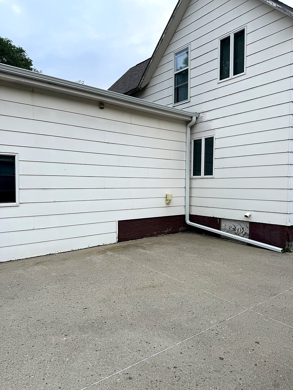 Gutter and downspout on a white lap-siding home